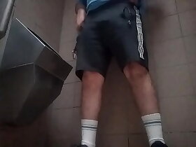 Young guy peeing in a public toilet